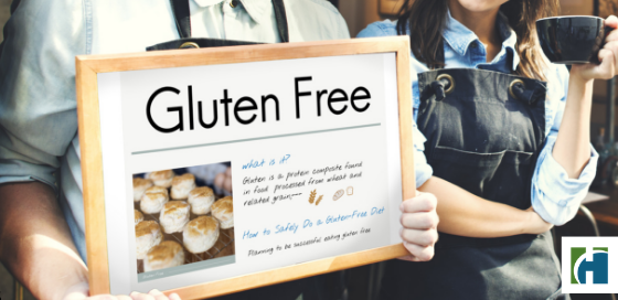 A man holds a gluten free sign with a smiling woman holding a cup of coffee in front of a restaurant.