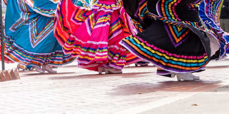 Dancers in colorful traditional Mexican skirts performing a folk dance during a cultural event.