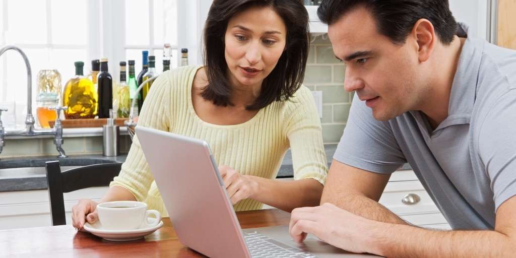 Couple using a laptop on their kitchen table