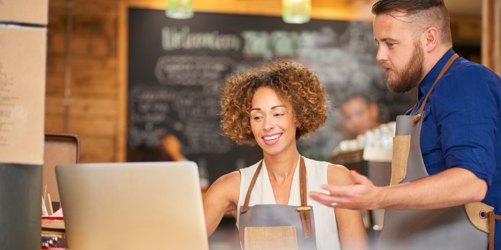 Owners of a coffee shop look through their latest financial figures on a laptop.