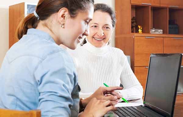 A woman using a laptop helping another woman in an office setting