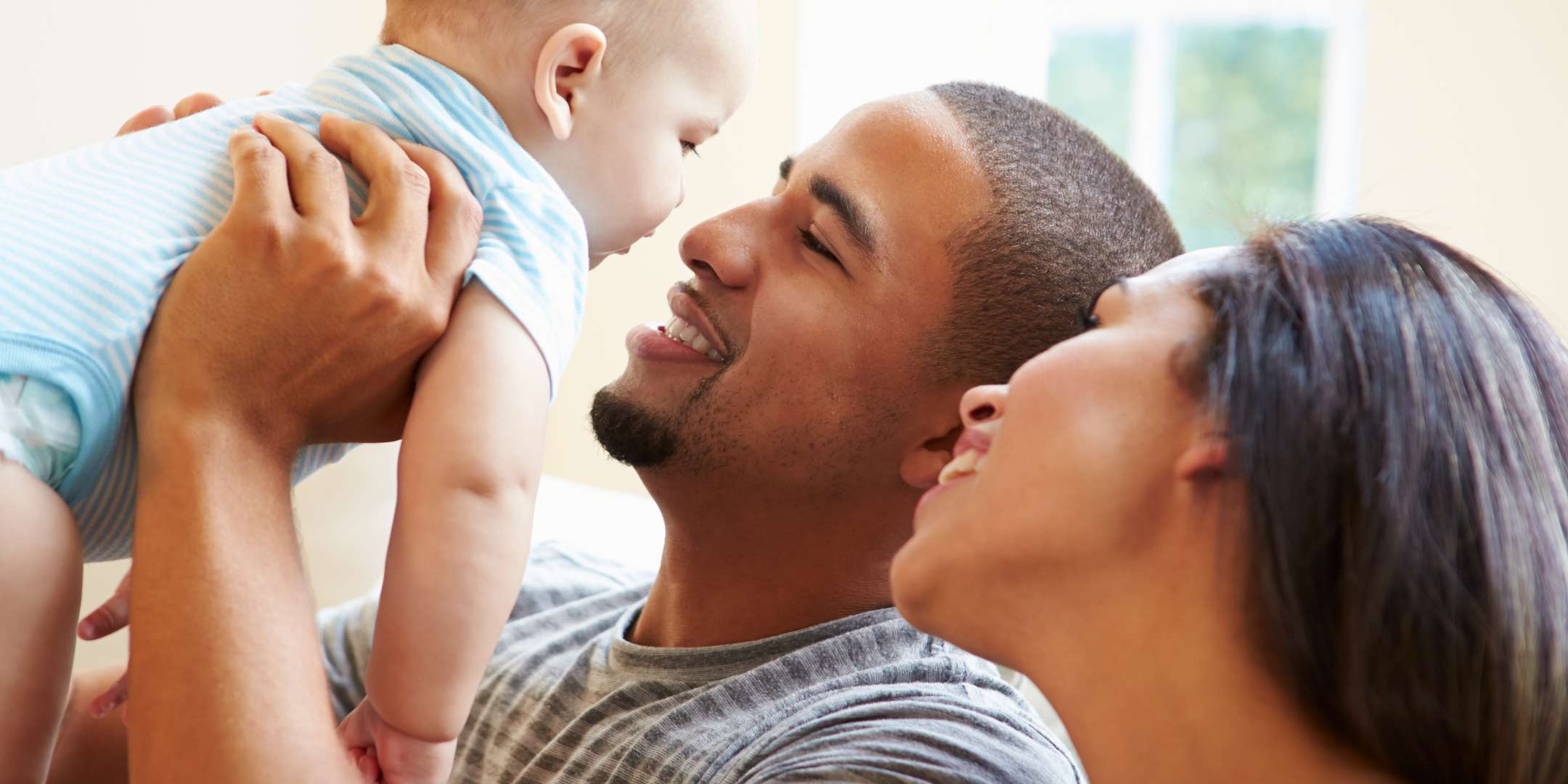 Young Family Playing With Happy Baby Son At Home