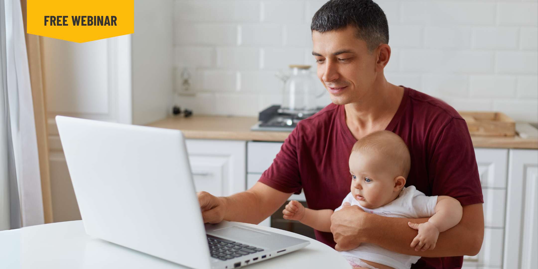 a person holding a baby and sitting at a table with a laptop